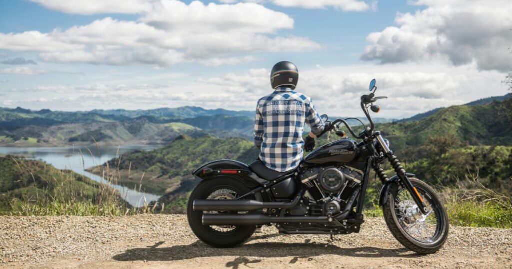 見晴らしのいい丘の上で、バイクにまたがって景色をながめる人
