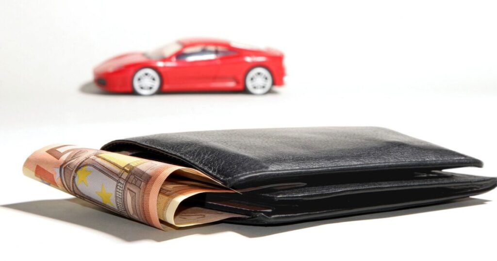 赤いスポーツカーの模型と、お札がはみ出た黒い財布