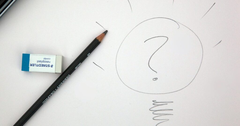 紙に鉛筆で描かれた、はてなマークの入った電球